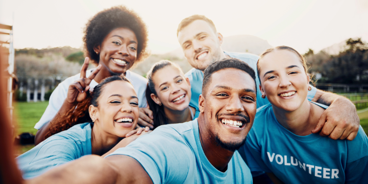 Group selfie of smiling volunteers in blue shirts, perfect for community focused nonprofit lenders.